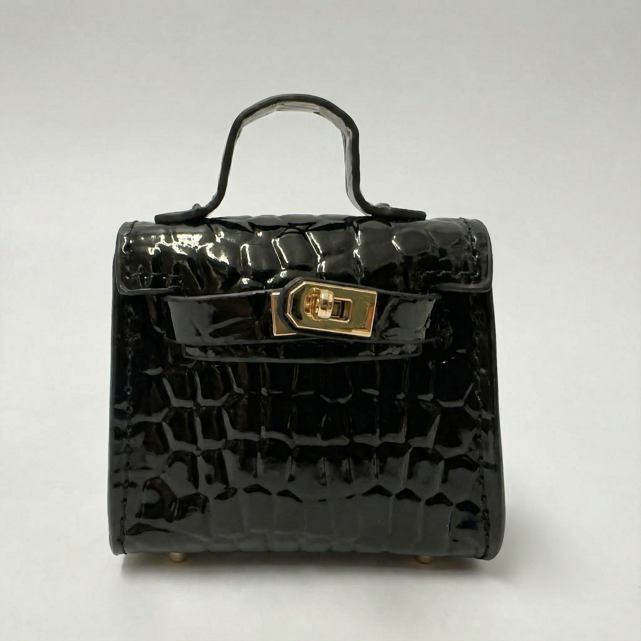 Black crocodile-patterned handbag with a gold clasp on a white background