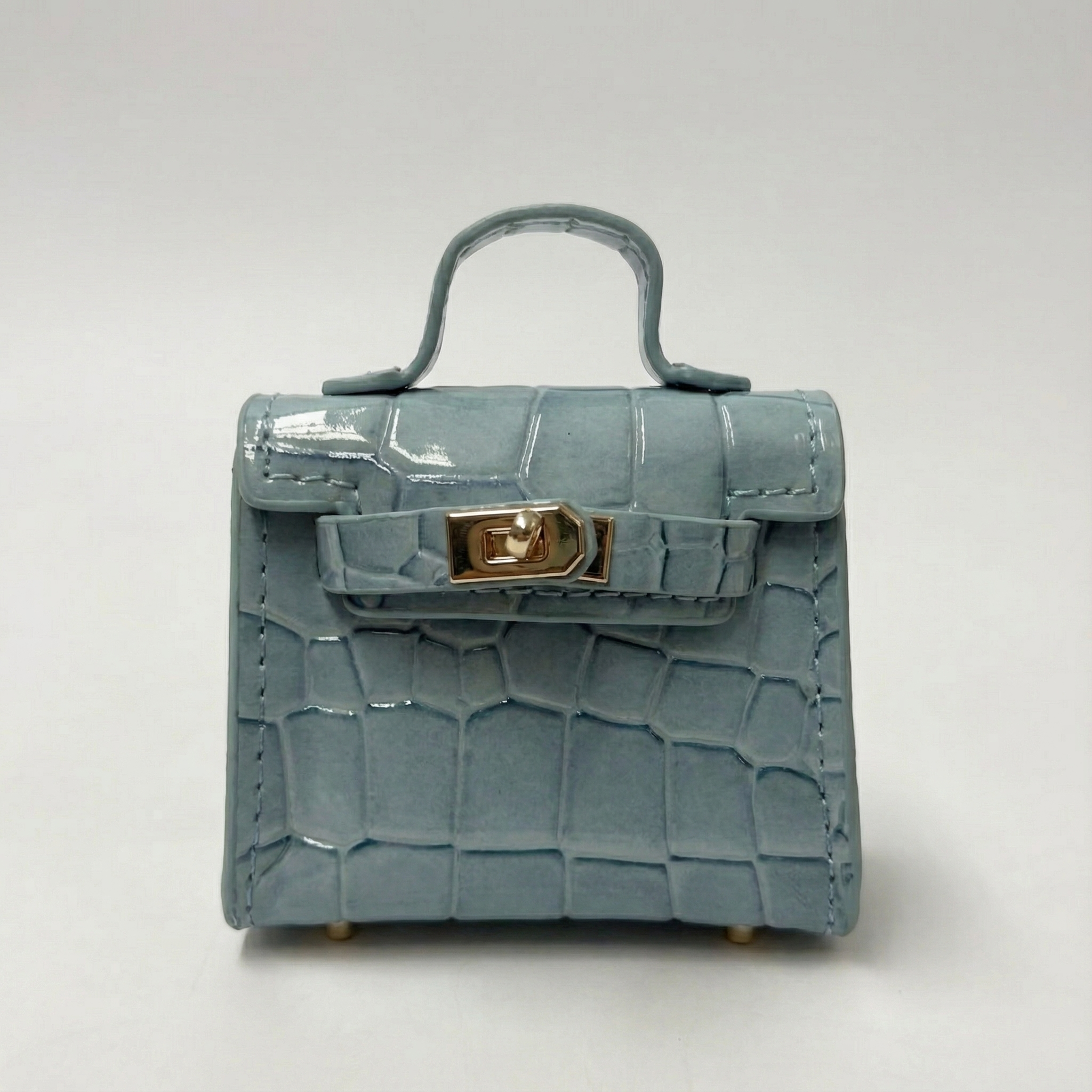 Blue crocodile-patterned handbag with a gold clasp on a white background
