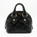 Black handbag with gold hardware on a white background