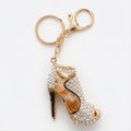 Gold high-heeled shoe keychain with rhinestones on a white background
