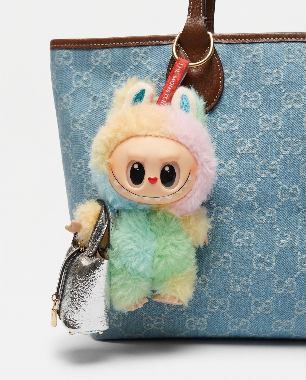Colorful plush toy with a small silver purse attached to a blue patterned bag.